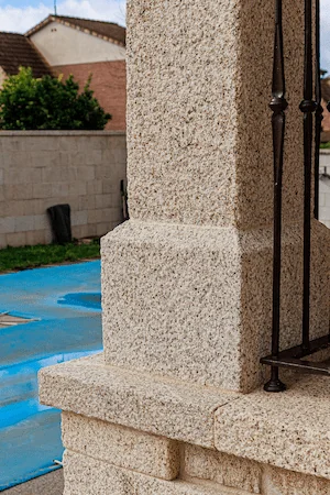 Base de columna cuadrada en granito rubio con acabado abujardado grueso, soporte sólido.