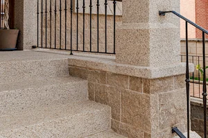 Detalle de base de columna en granito rubio con acabado abujardado grueso, soporte decorativo.