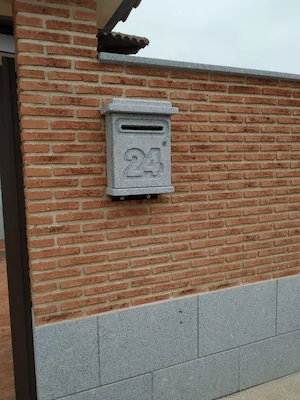Buzón en granito gris abujardado con número de vivienda tallado, funcional y duradero.