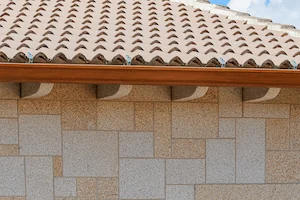 Canecillos decorativos en granito rubio con acabado abujardado artesanal.