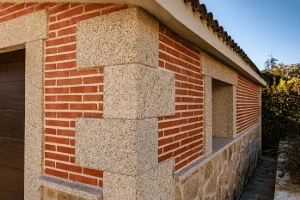 Fachada combinando ladrillo visto y esquinas en granito rubio.