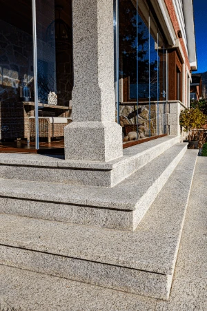 Escalera y columna en granito rubio abujardado, diseño clásico para exterior.