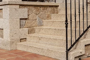 Escalera en granito rubio con acabado abujardado grueso, ideal para entradas.
