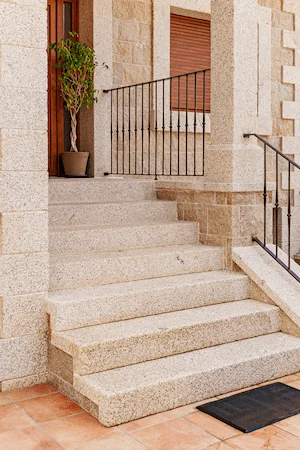 Escalera de granito rubio con acabado picado gordo, estilo tradicional y robustez.