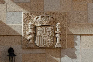Escudo de España tallado en granito rubio, detalle artesanal distintivo.