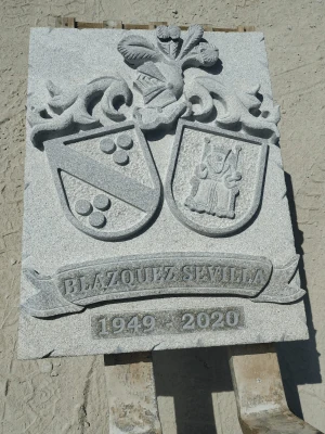 Escudo tallado artesanal en granito blanco, detalle artístico con acabado fino.