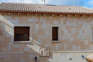 Fachada de granito, en color rubio y acabado abujardado con escudo de España tallado a mano.