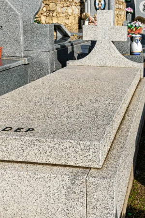 Lápida en granito gris abujardado con cruz en una pieza, diseño tradicional y duradero.