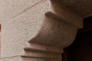 Ménsula en granito blanco cristal abujardado, detalle arquitectónico elegante.