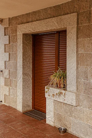 Ventanal con esquinas en granito rubio abujardado y pared rústica.