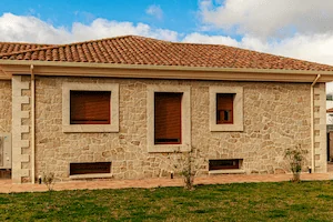 Vivienda con fachadas de granito, color rubio con acabados rústico y abujardado grueso.